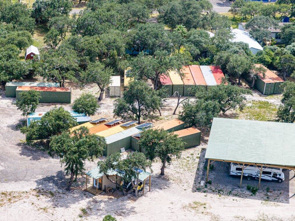 Steel storage containers among the live oaks, some with solar panels, seen from the air
