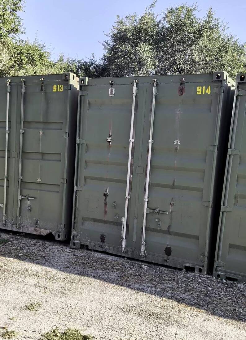 Green 9 by 40 foot steel storage containers with drive-up doors under the live oaks